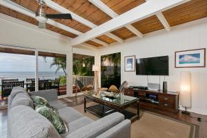 a living room with a couch and a tv at Waimea Bay Shoreline House in Haleiwa