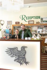 two men standing behind a counter with a rooster on it at Hotel Restaurant Schwarzer Adler 