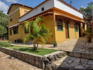 a yellow house with a palm tree in front of it at Hospedaria Estrada Real in Tiradentes
