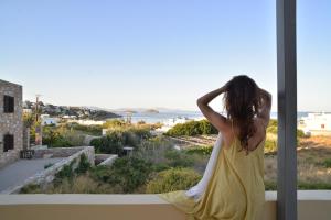 a woman in a yellow dress looking out at the ocean at Marina's Studios in Azolimnos Syros