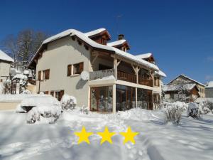 uma casa coberta de neve com três estrelas em Gîte 829 Montagnes du Jura avec Spa et Sauna classé 3 étoiles em Foncine-le-Haut