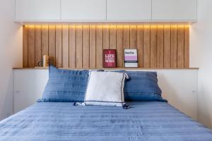 a bedroom with a blue bed with a wooden headboard at Trend Nova Carlos Gomes - 406 in Porto Alegre