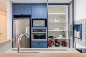 a kitchen with blue cabinets and a refrigerator at Trend Nova Carlos Gomes - 406 in Porto Alegre