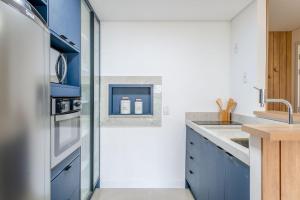 a kitchen with blue cabinets and a stainless steel refrigerator at Trend Nova Carlos Gomes - 406 in Porto Alegre
