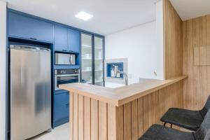 a kitchen with blue cabinets and a stainless steel refrigerator at Trend Nova Carlos Gomes - 406 in Porto Alegre