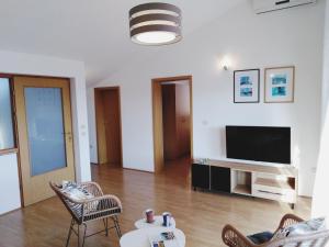 een woonkamer met een tv en een bank en stoelen bij Sea View K Loft in Rabac