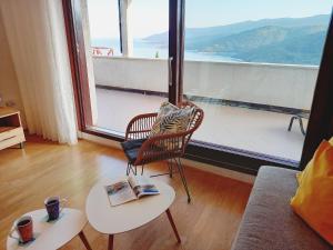 een woonkamer met een stoel en tafels en een groot raam bij Sea View K Loft in Rabac