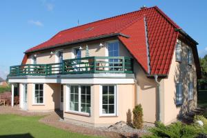 une grande maison avec un toit rouge dans l'établissement Landsitz Rügen, à Glowe