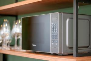 a microwave sitting on a shelf with wine glasses at Paseo Del Molino - 703 in Caxias do Sul