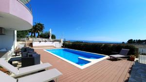 a backyard with a swimming pool and a deck with chairs at SEA VIEW- spacious apartment with shared pool in Split