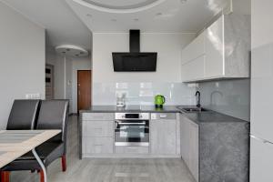 uma cozinha com armários brancos, um lavatório e uma mesa em Wave Apartments - Solvo 2 em Gdańsk