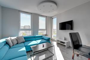 Sofá azul en la sala de estar con ventanas en Wave Apartments - Solvo 2 en Gdansk