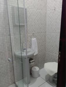 a white bathroom with a toilet and a sink at Pousada Jesus Misericordioso in Aparecida