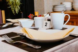 a table topped with plates and cups and utensils at Plougastel House B&B in Westport