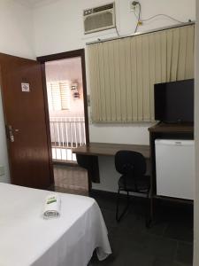 a room with a bed and a desk and a television at HOTEL BELA VISTA NOVA ODESSA in Nova Odessa