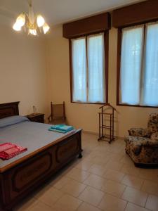 um quarto com uma cama, uma cadeira e janelas em Casa Timoteo em Mantova