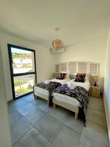 a bedroom with two beds and a large window at Superbe T3 NEUF VUE MER in Propriano