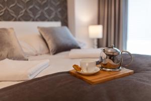 a tray with a tea kettle and a cup on a bed at Apartament Greno Kielce in Kielce