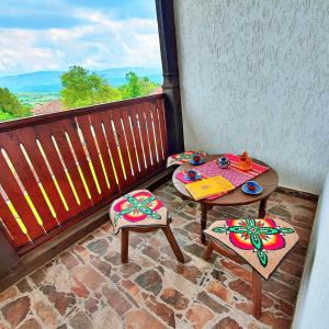 um pátio com 2 mesas e cadeiras numa varanda em Къща за гости Песента на колелетата - Жеравна em Zheravna