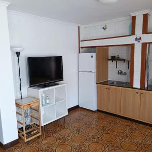 a kitchen with a white refrigerator and a tv at CASA ALTA OLIVA PLAYA in Oliva