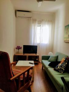 ein Wohnzimmer mit einem grünen Sofa und einem Fernseher in der Unterkunft Victoria home in Málaga