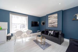 a living room with blue walls and a black couch at SEA HIGH QUALITY ROOF TERRACE Slp 6 TWO BED FLT in Brighton & Hove