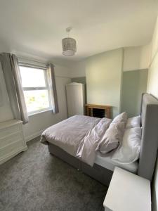 a bedroom with a bed with white sheets and a window at Ifan cottage - two bedroom cottage in Meliden
