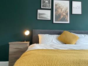 een slaapkamer met een bed met een gele deken en foto's aan de muur bij Durham 3 Bedroom House With Parking in Durham