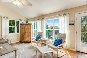 a living room with two chairs and windows at Compass Rose II in Folly Beach