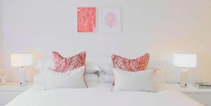 a white bedroom with a white bed with red and white pillows at St Moritz Hotel and Cowshed Spa in Polzeath +37 photos