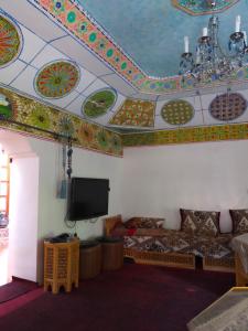 a living room with a tv and a ceiling with colorful tiles at Gîte tizinoubadou in Aït Youguine