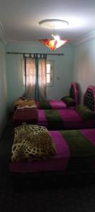a group of beds in a room with purple sheets at Gîte tizinoubadou in Aït Youguine