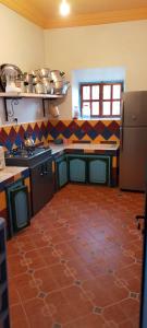 a kitchen with a red tile floor in a kitchen at Gîte tizinoubadou in Aït Youguine
