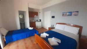 a bedroom with a blue bed and a kitchen at Rooms to let Spiropali in Piqeras