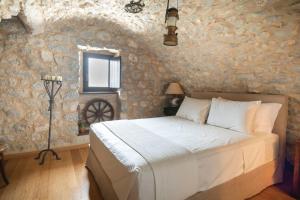 a bedroom with a bed and a stone wall at Fameliti Casa Torre - Historic Maniot Tower House in Stavríon