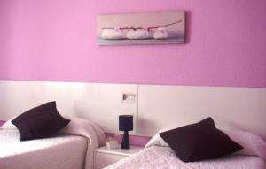 1 dormitorio con 2 camas y pared de color rosa en Pensión Room Pamplona en Pamplona