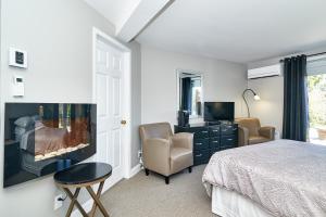 una camera con letto, camino e TV di Auberge Aux Deux Pères a Magog-Orford