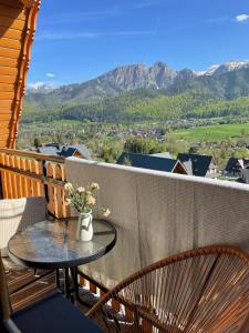a table and chairs on a balcony with mountains at Dom na Wierchu in Kościelisko