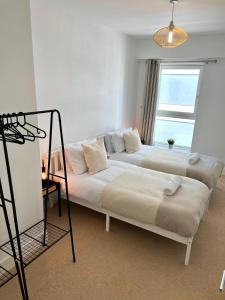 2 Bedroom Serviced Apartment with Free Parking, Wifi & Netflix, Basingstoke في باسينغستوك: سريرين في غرفة مع نافذة
