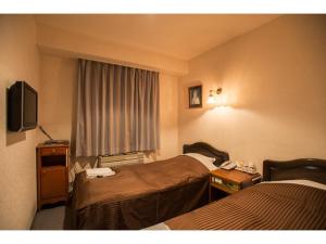 una camera d'albergo con due letti e una televisione di Famy Inn Makuhari - Vacation STAY 16036v a Chiba