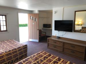 a hotel room with a bed and a flat screen tv at DEEPWELL MOTEL in Owego +4 photos