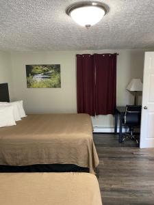 a bedroom with a bed and a desk with a chair at The New Lantern Motel in Allegany