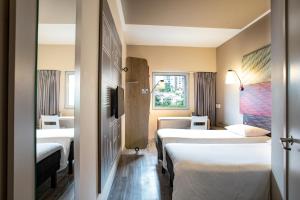 a hotel room with two beds and a window at Hotel Ibis Cali Granada in Cali