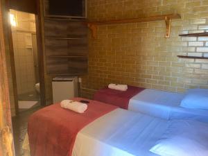 two beds in a room with a brick wall at Pousada Do Sol in Conceição da Barra