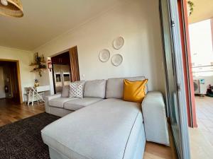 uma sala de estar com um sofá cinzento e almofadas amarelas em My Place em Portimão