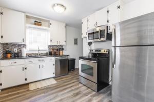 a kitchen with white cabinets and a stainless steel refrigerator at 3 Bedrooms House in Waldo Kansas City in Kansas City