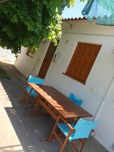 a wooden table and two blue chairs next to a building at EVRIAKI'S HOUSE in Apidias Lakos