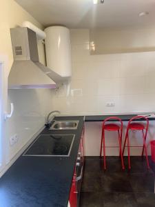 una cocina con fregadero y 2 taburetes rojos en Apartamento parque las llamas, en Santander