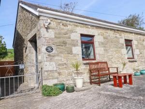 een stenen cottage met een bank en een raam bij Stable Cottage in Newquay