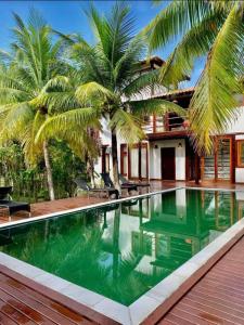 a swimming pool in front of a house with palm trees at Vivant Eco Resort apartamento in Barra Grande